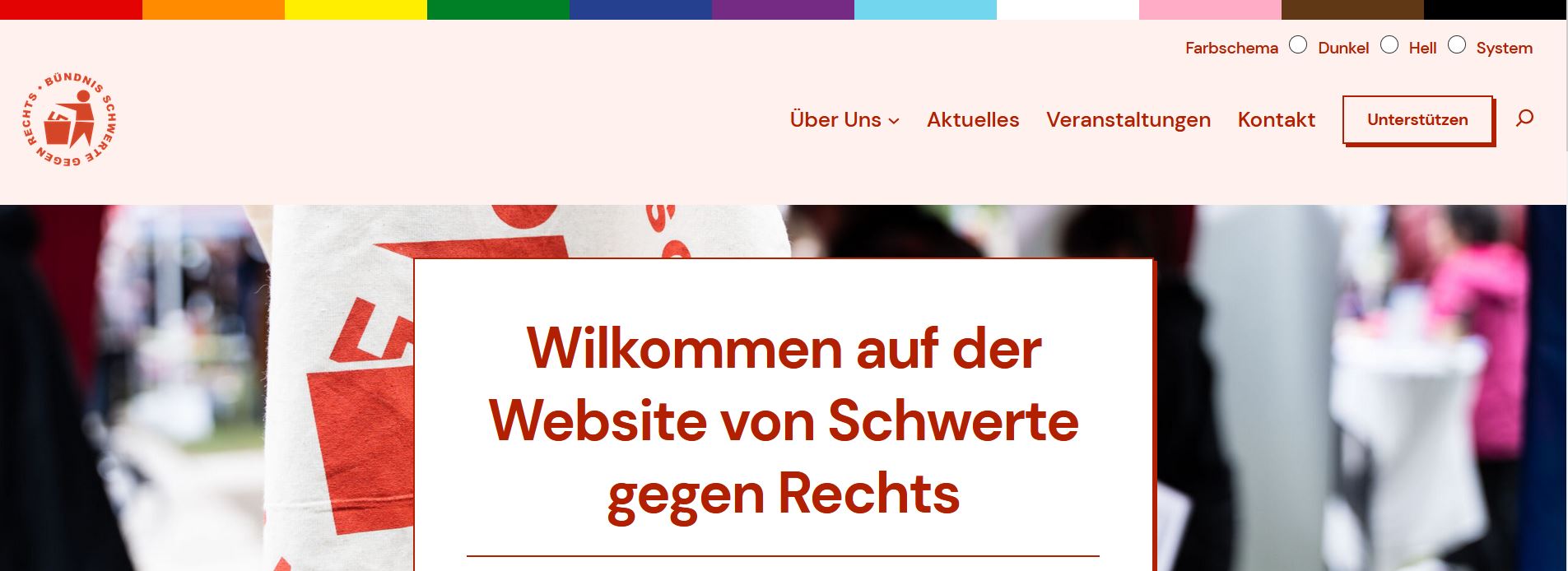 Screenshot der neuen Webseite von Schwerte gegen Rechts. Oben ist ein Banner mit den Farben der Prideflag darunter ein Menü und Einstellungen zu einem Dunkelmodus. Darunter steht "Willkomen auf der Webseite von Schwerte gegen Rechts".