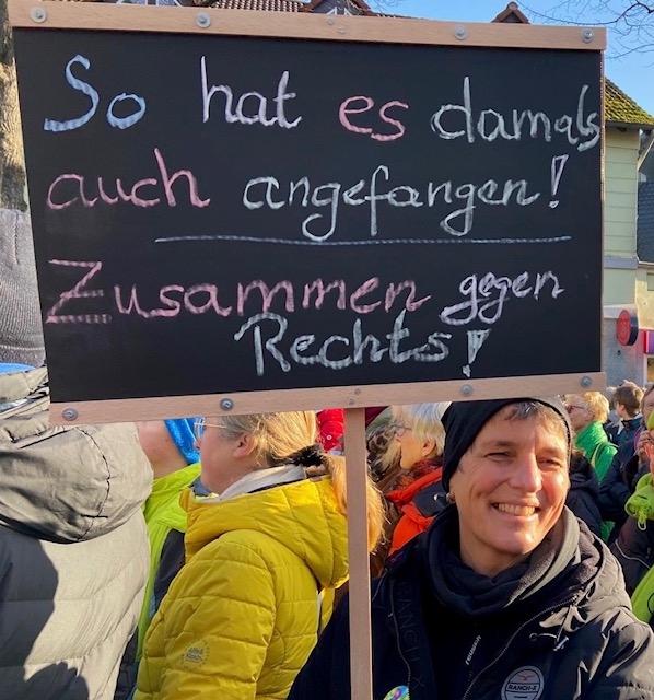 Foto von Angela Mandelartz mit einem Demoschild „So hat es damals auch angefangen“.