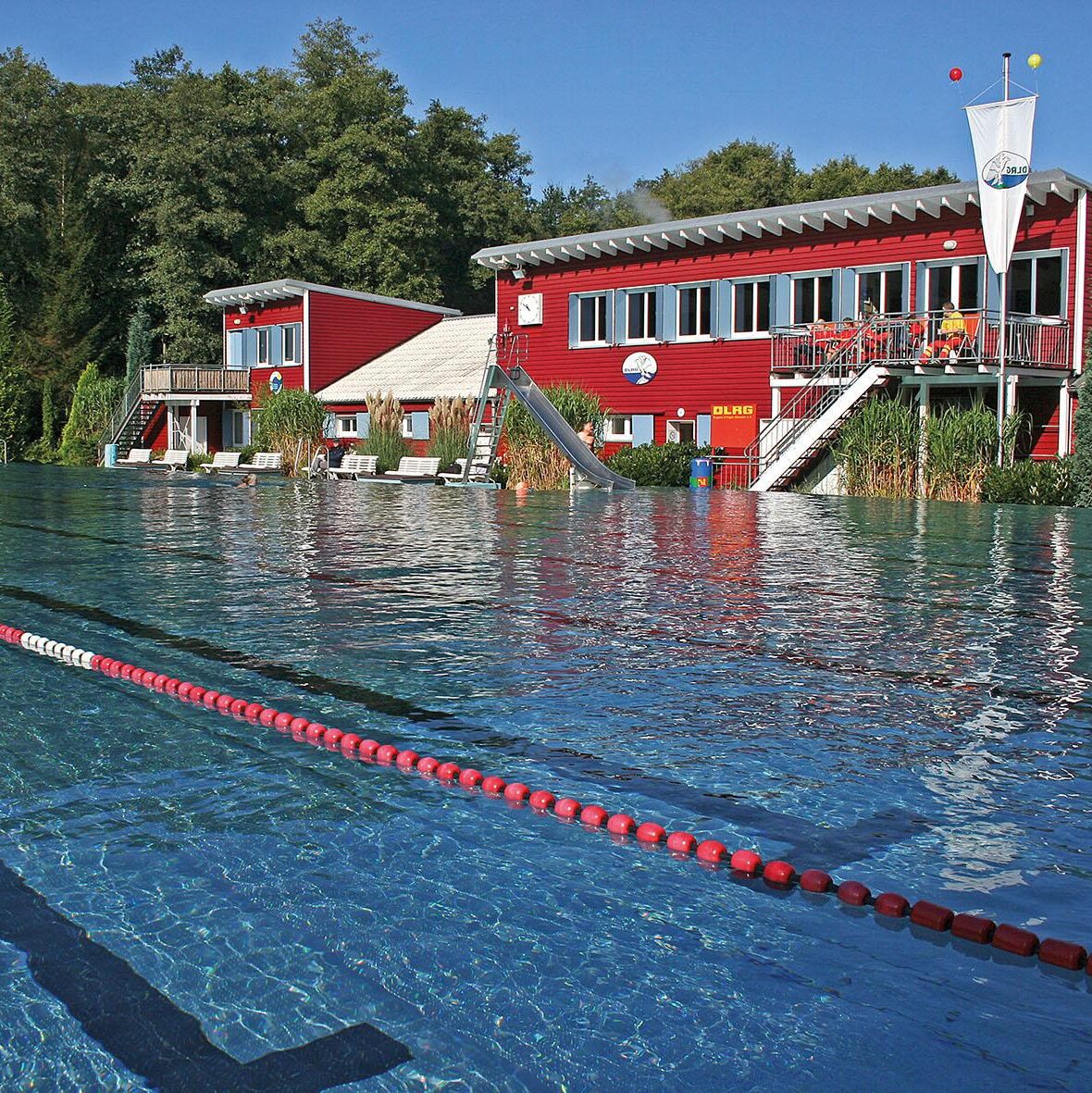 Foto des Elsebades in Schwerte, einem Freibad. Zu erkennen i8st ein Schwimmbecken im Hintergrund Gebäude mit roter Fassade.