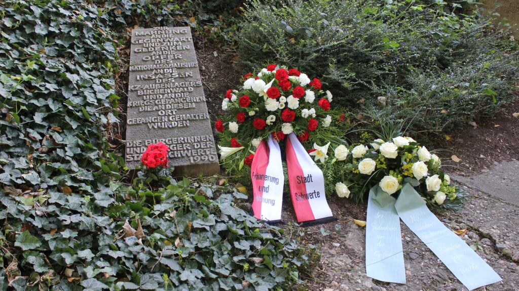 Am Gedenkstein mit der Aufschrift "Zur Mahnung an die Gegenwart und zum Gedenken an die Opfer des Nationalsozialismus an die Insassen des KZ-Außenlagers Buchenwald und an die Kriegsgefangenen die an diesem Ort gefangen gehalten wurden - Bürgergerinnen und Bürger der Stadt Schwerte 1990" liegt ein Kranz mit Schlefe und Aufschrift "Erinnerung und Mahnung - Stadt Schwerte" und ein kleinerer Kranz mit der Aufschrift "In Gedenken an die Opfer - Nie wieder Faschismus - Bündnis gegen Rechts".